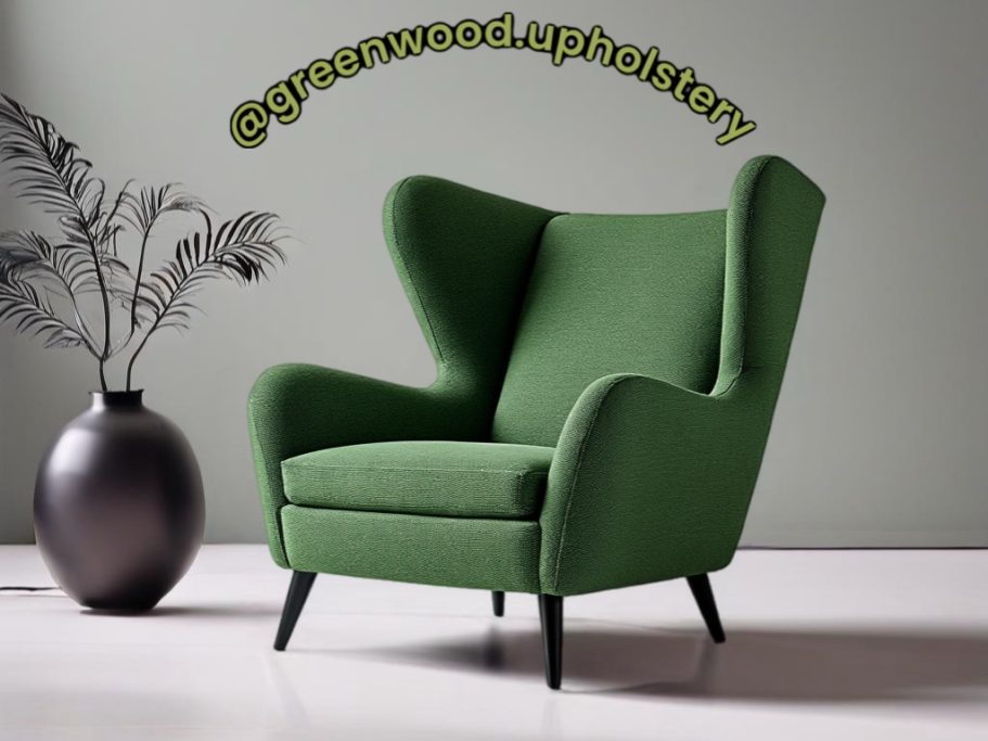 Green wingback chair next to a black vase and plant against a neutral wall.