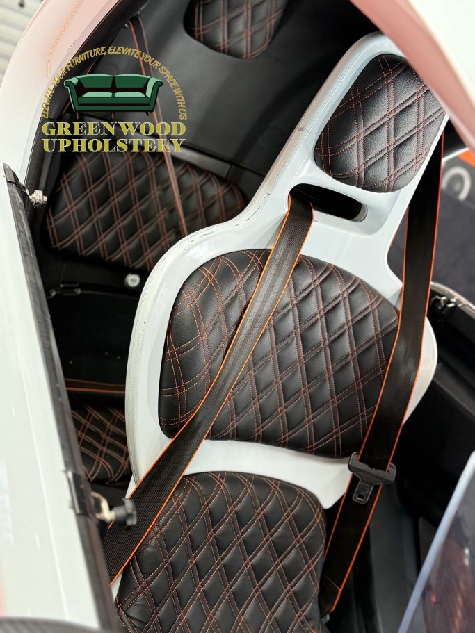 Brown quilted seat with white detailing and safety harness in a vehicle interior.